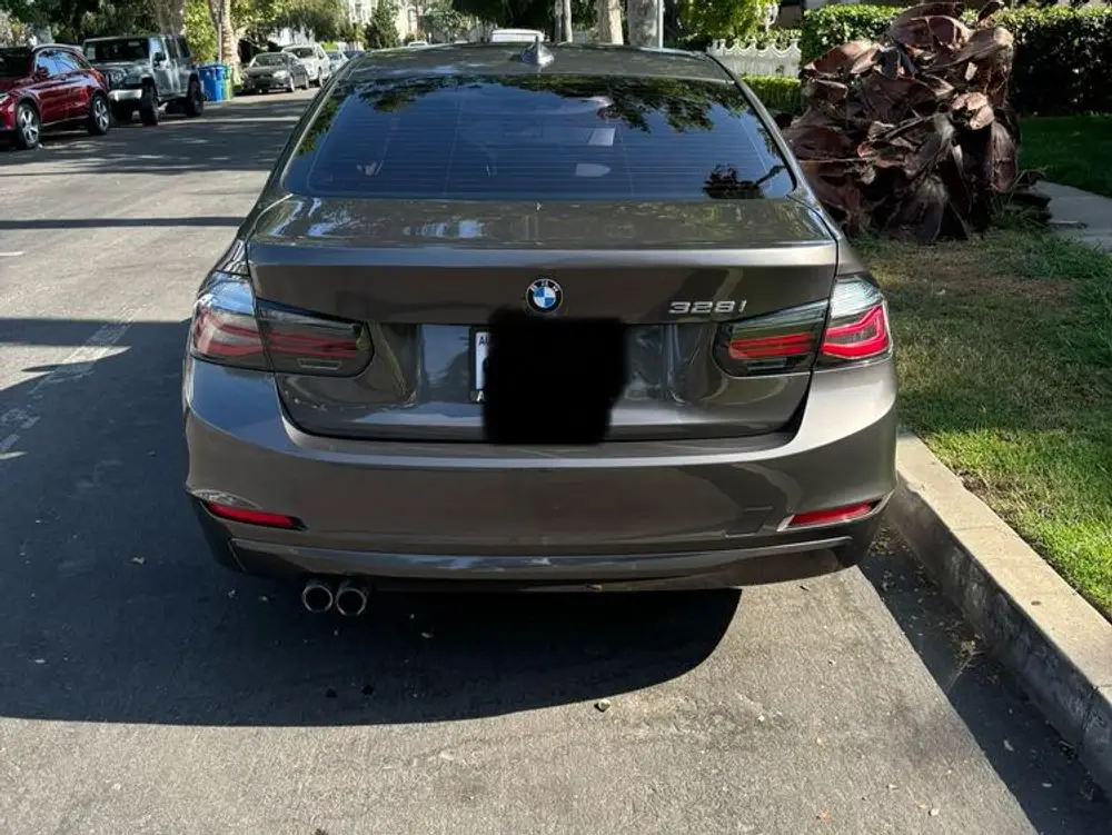 Rear view of a gray BMW 328i sedan parked on a tree-lined street